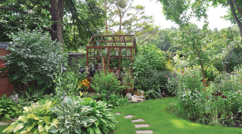 In the lush green beds of the backyard, the Victory Orangery greenhouse is barely visible.